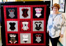 Woman stands by quilt
