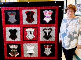 Woman stands by quilt
