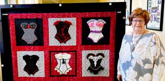 Woman stands by quilt
