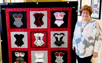 Woman stands by quilt
