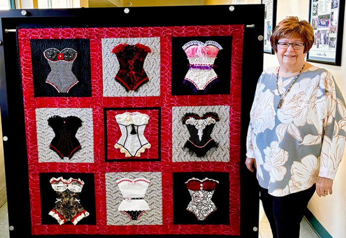 Woman stands by quilt