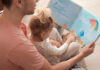 Father and his daughter reading book on floor in children room