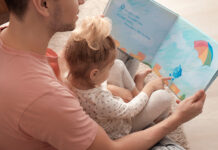 Father and his daughter reading book on floor in children room