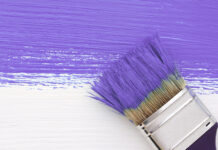 Stripe of purple paint with a paintbrush on white