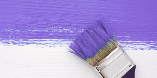 Stripe of purple paint with a paintbrush on white