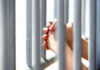 Hands Grasping Metal Bars in Light