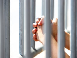 Hands Grasping Metal Bars in Light