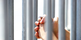 Hands Grasping Metal Bars in Light